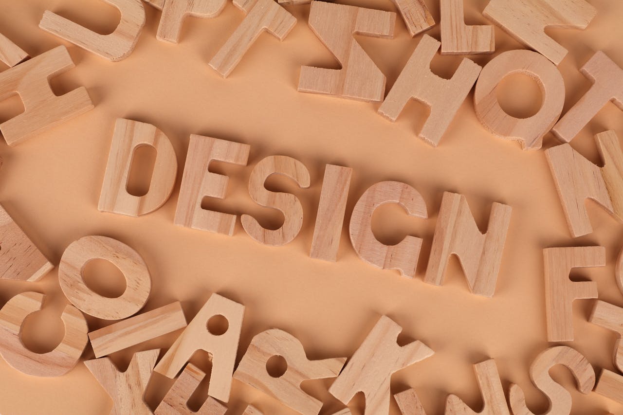 Wooden letters arranged to form the word design on a brown background, top view.